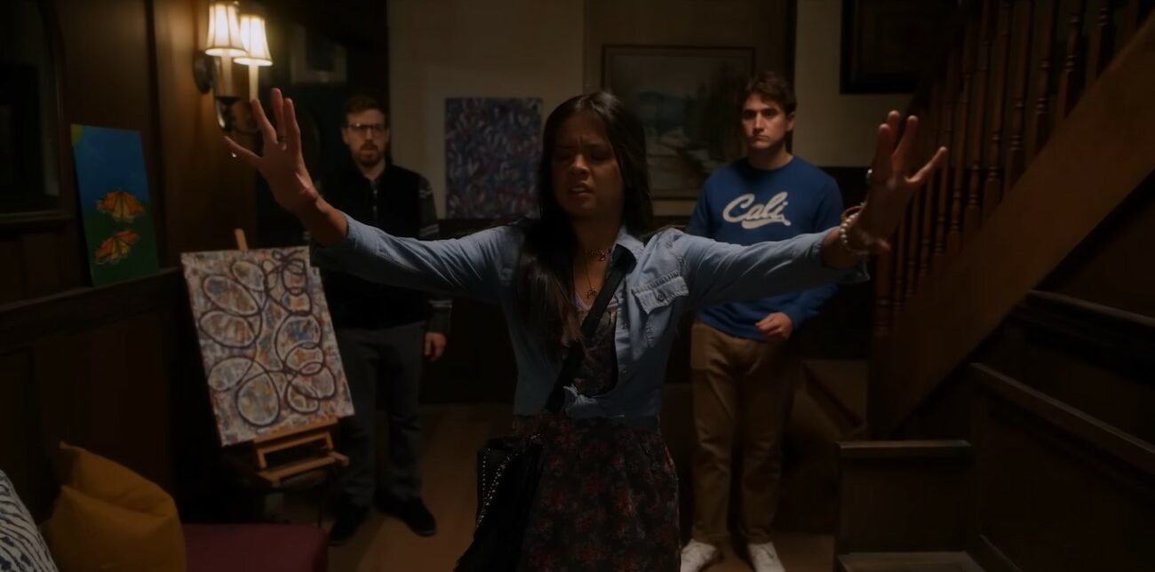 A psychic puts her arms out as "feelers" to look for some spiritual energy. Two men stand a few feet behind her, watching her communicate with spirits.