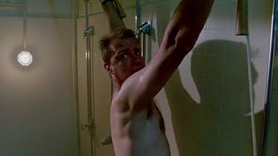 Schneider looks with terror at someone off-screen as he stands tied to a shower.